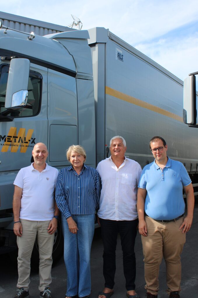 Quatre membres de l'équipe Metal-X devant un camion de l'entreprise